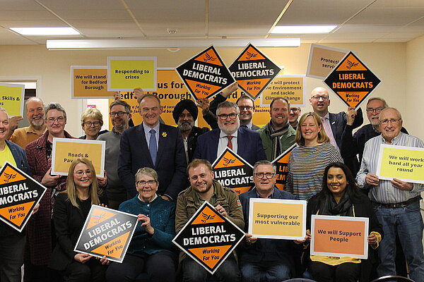 A group of Liberal Democrats holding gold diamond Liberal Democrat posters and posters with slogans 