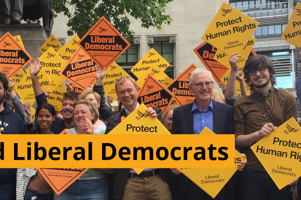 A group of Liberal Democrats holding gold diamond posters saying Liberal Democrats and Protect Human Rights