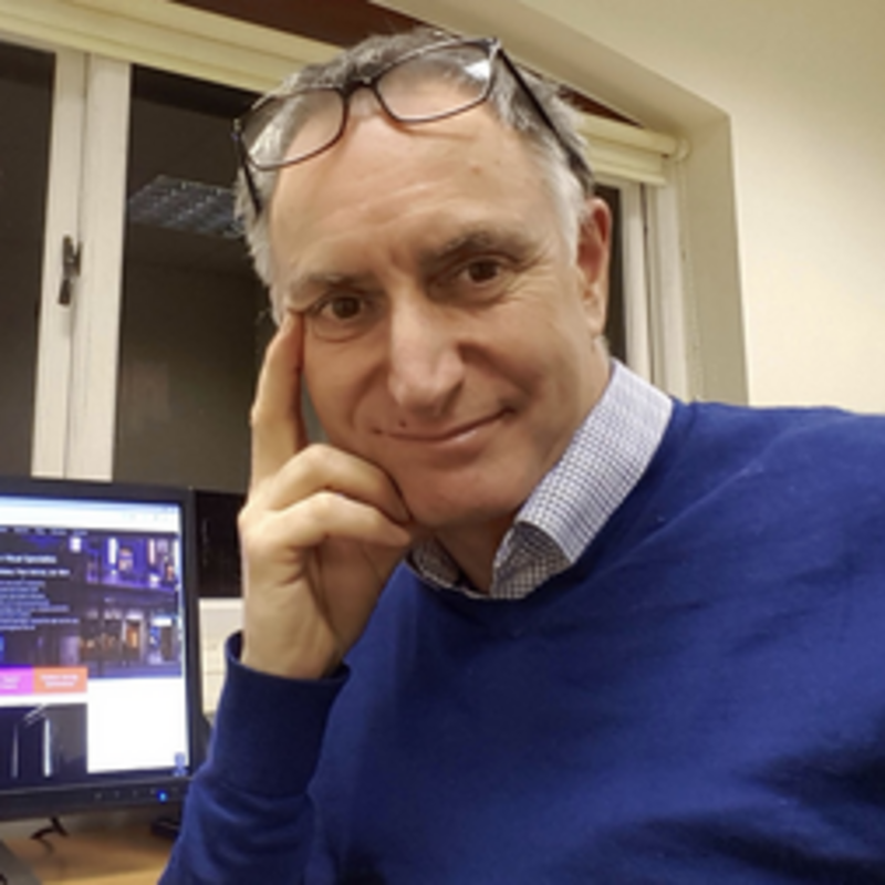 Head and shoulders shot of John Shreeve in blue jumper in front of computer screen