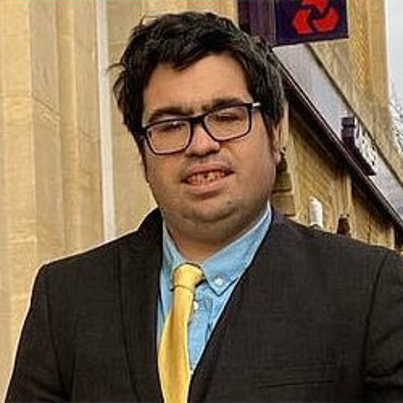 Head and shoulders photo of Adam Robertson wearing a suit outside a local bank branch