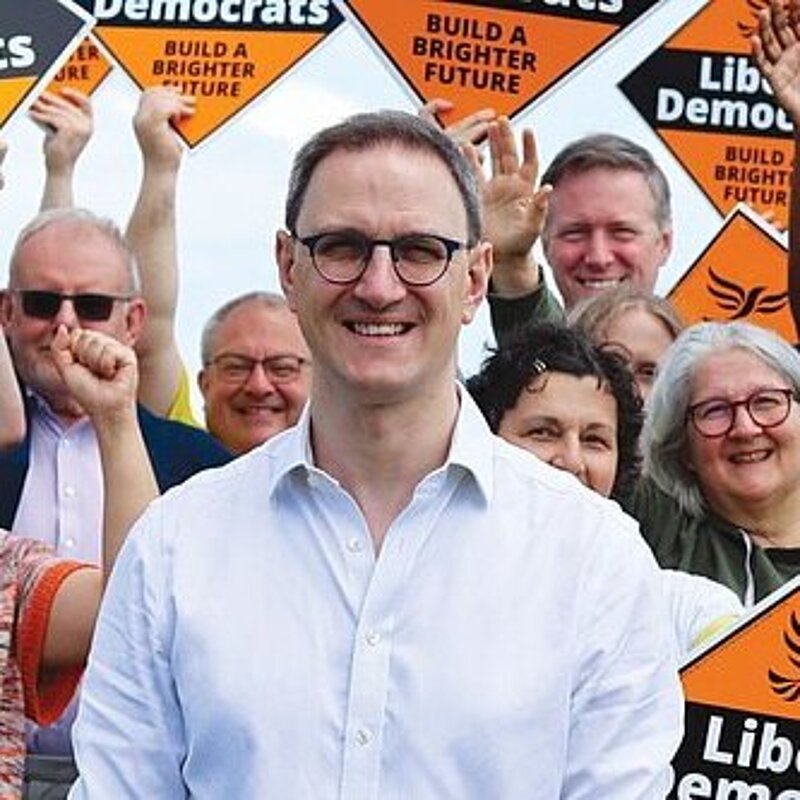 Ian Sollom in front of a group of enthusiastic people holding orange Liberal Democrat diamond posters