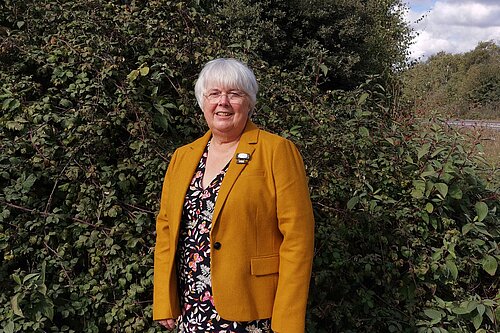 Charlotte Cane standing next to a hedge